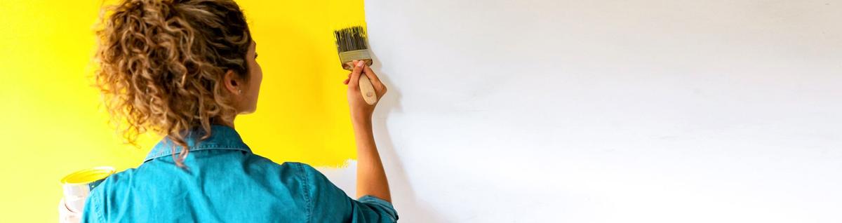 mulher pintando a parede de amarelo 