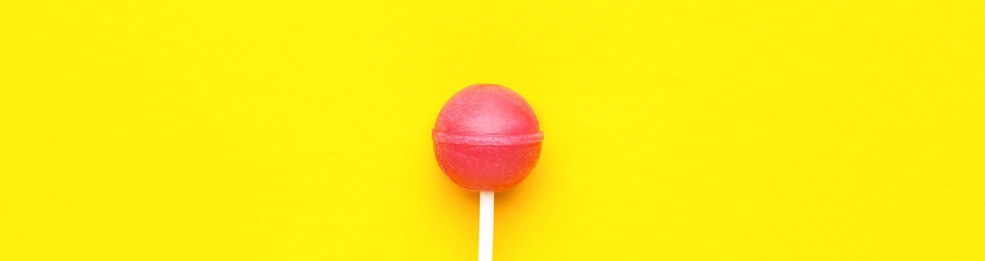 doce pirulito vermelho em fundo amarelo