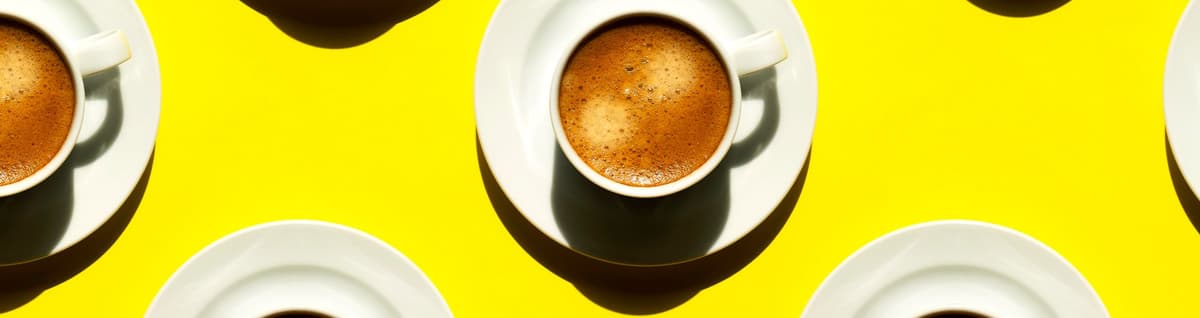xícaras de café formando padrão em superfície amarela