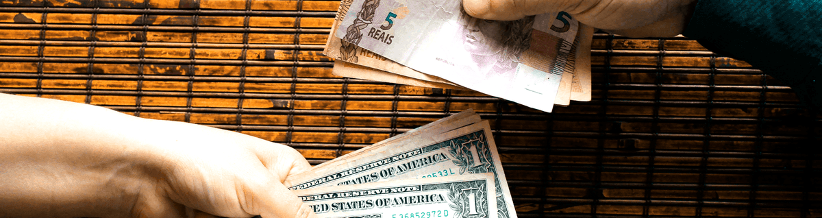pessoas trocando cédulas de reais e dólar 