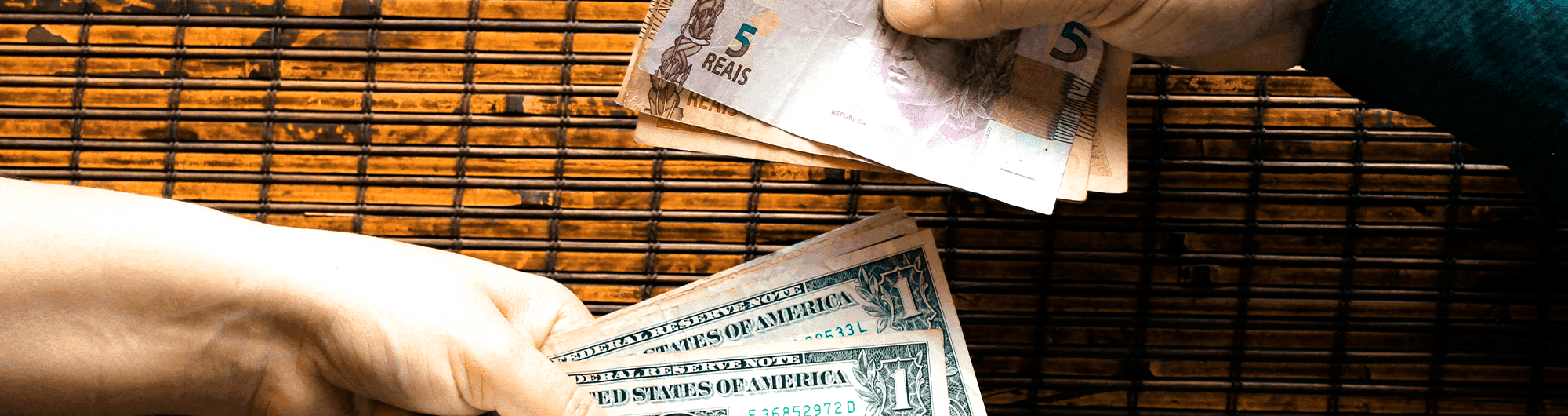 pessoas trocando cédulas de reais e dólar 