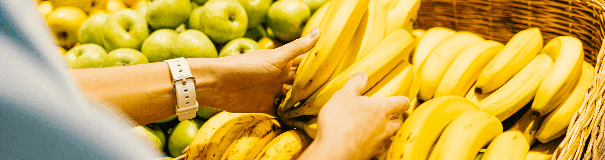 pessoa escolhendo cacho de bananas em supermercado