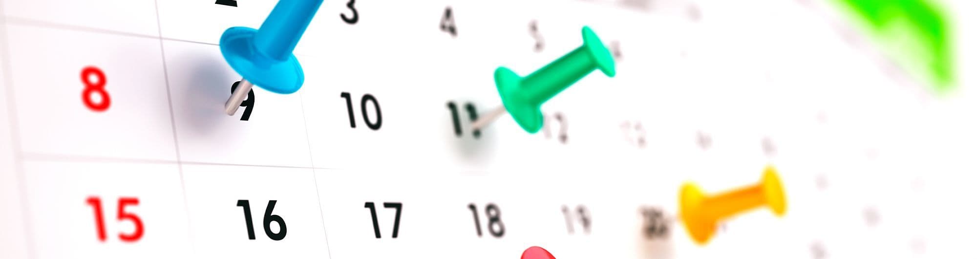 calendário marcado por alfinetes coloridos 
