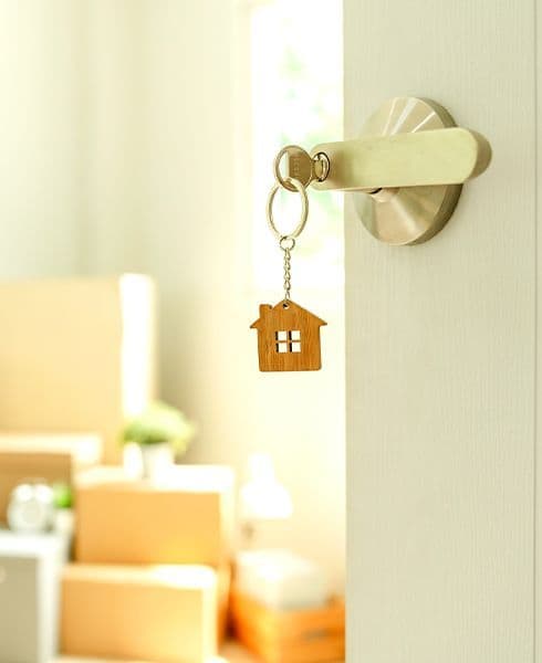 chave de casa com chaveiro em formato de casa presa em porta