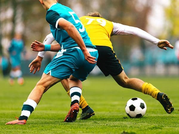 jogadores de futebol adversários disputando pela bola em partida