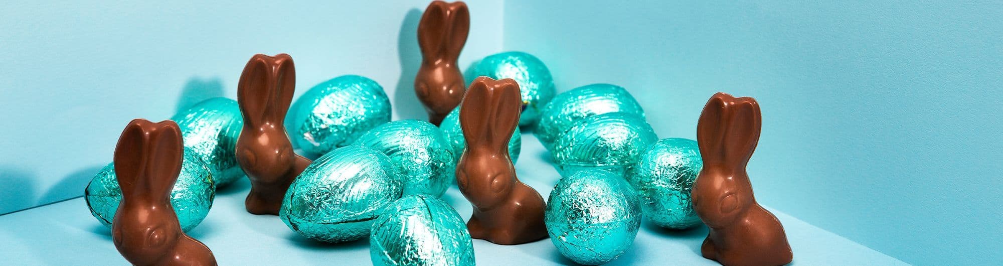 chocolate em formato de coelho e ovos sobre fundo azul