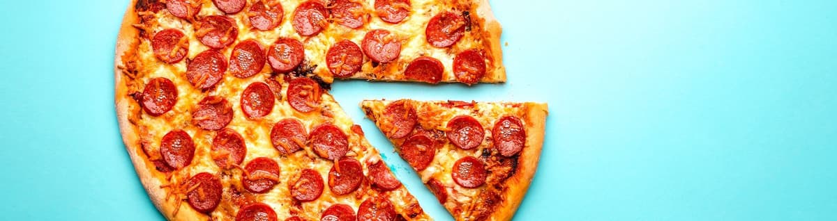 pizza inteira com fatia separada sobre fundo azul