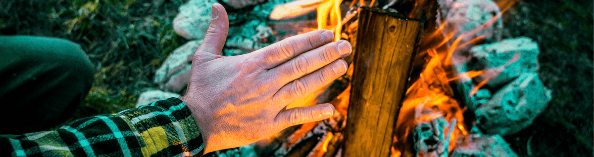 pessoa aquecendo as mãos em fogueira 