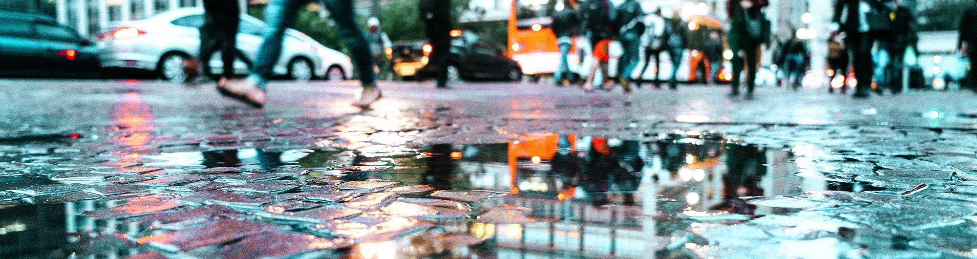 pessoas se movimentando em avenida molhada