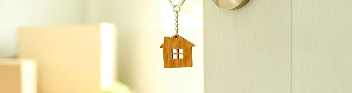 chave de casa com chaveiro em formato de casa presa em porta