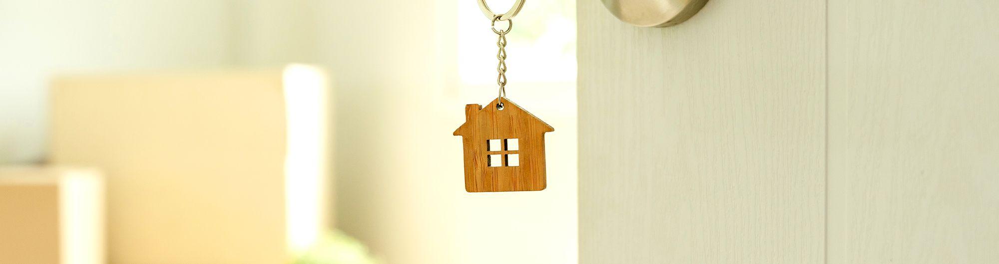 chave de casa com chaveiro em formato de casa presa em porta