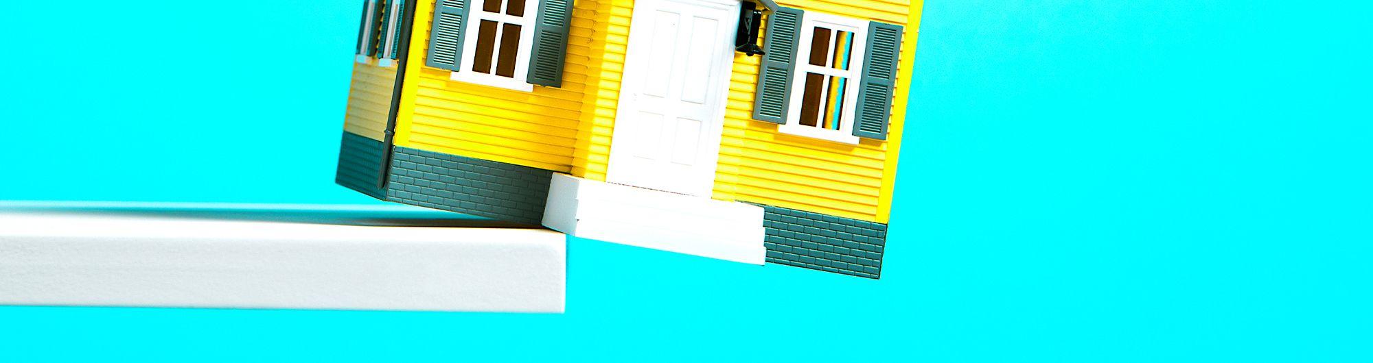 forma de casa caindo de plataforma em fundo azul