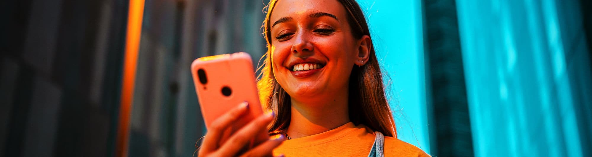 jovem loira blusa amarela sorrindo celular
