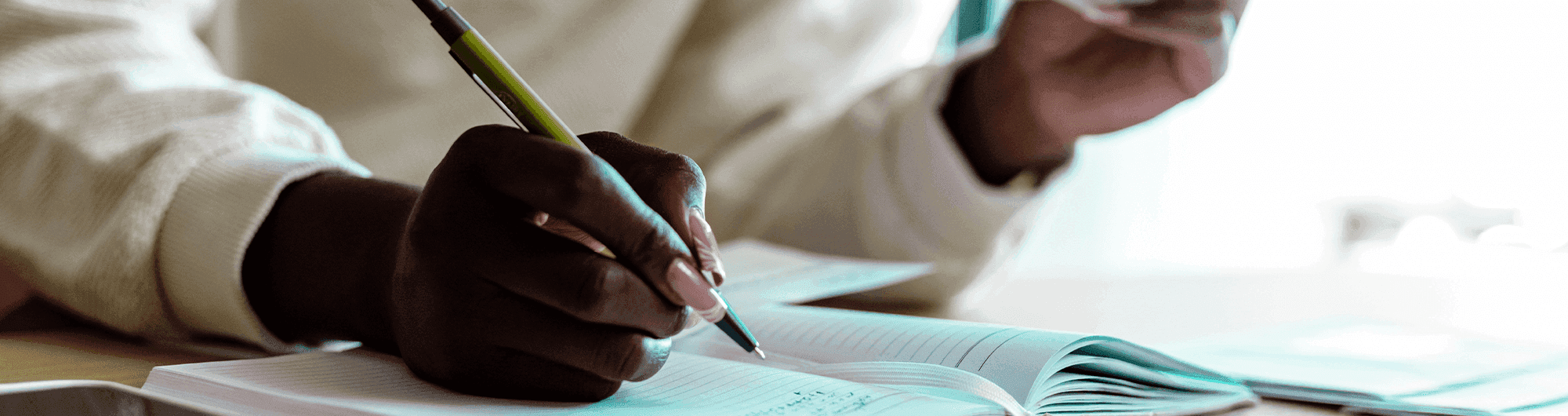 pessoa fazendo anotações em caderno com dólar em mãos