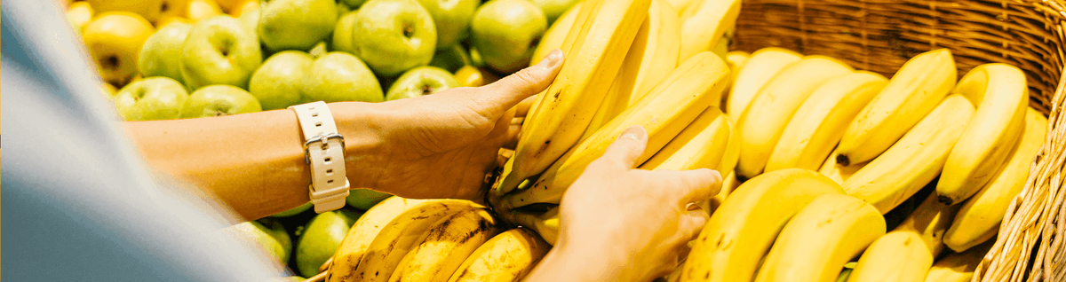 pessoa escolhendo cacho de bananas em supermercado