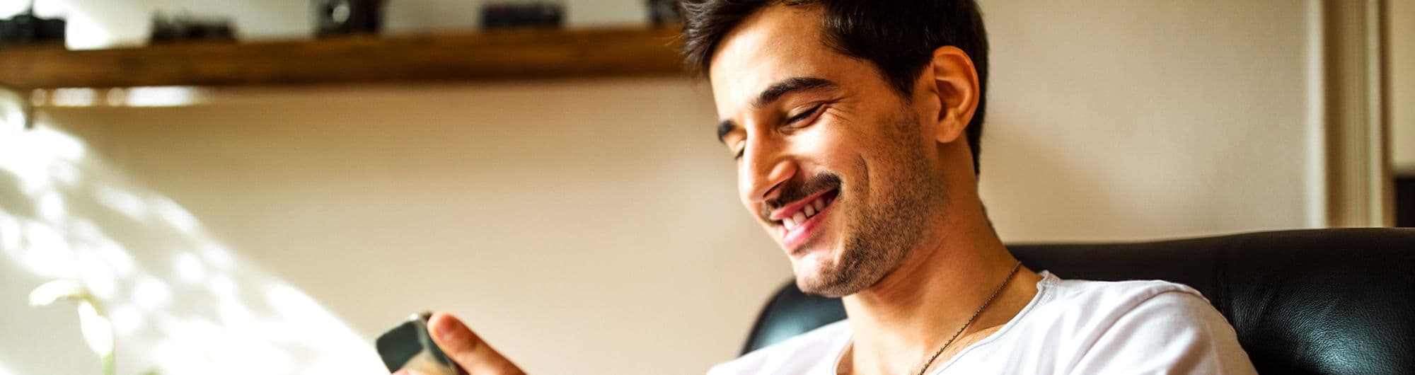 homem sorrindo olhando para celular