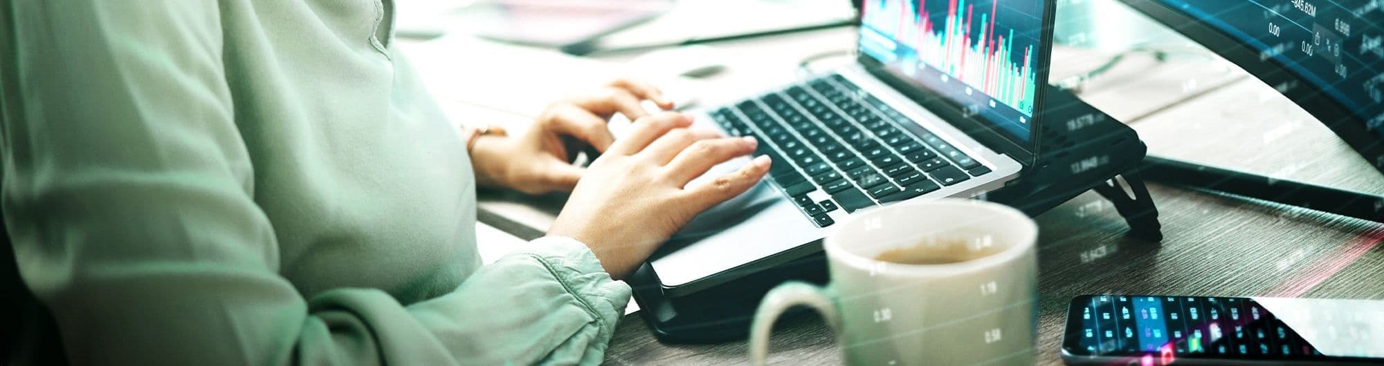 mulher negra usando computador com gráficos do mercado financeiro