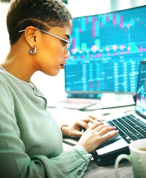 mulher negra usando computador com gráficos do mercado financeiro