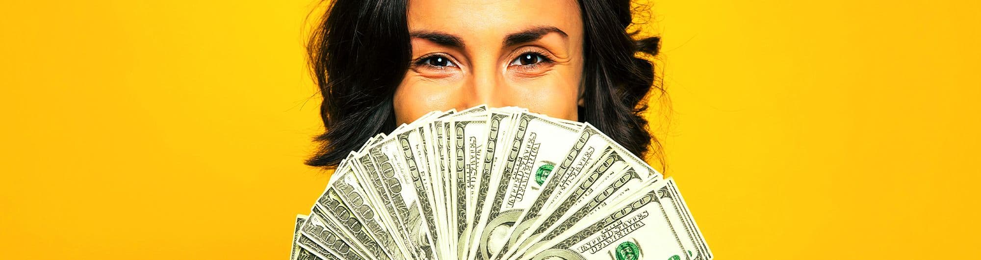 mulher segurando notas de dólar sobre fundo amarelo
