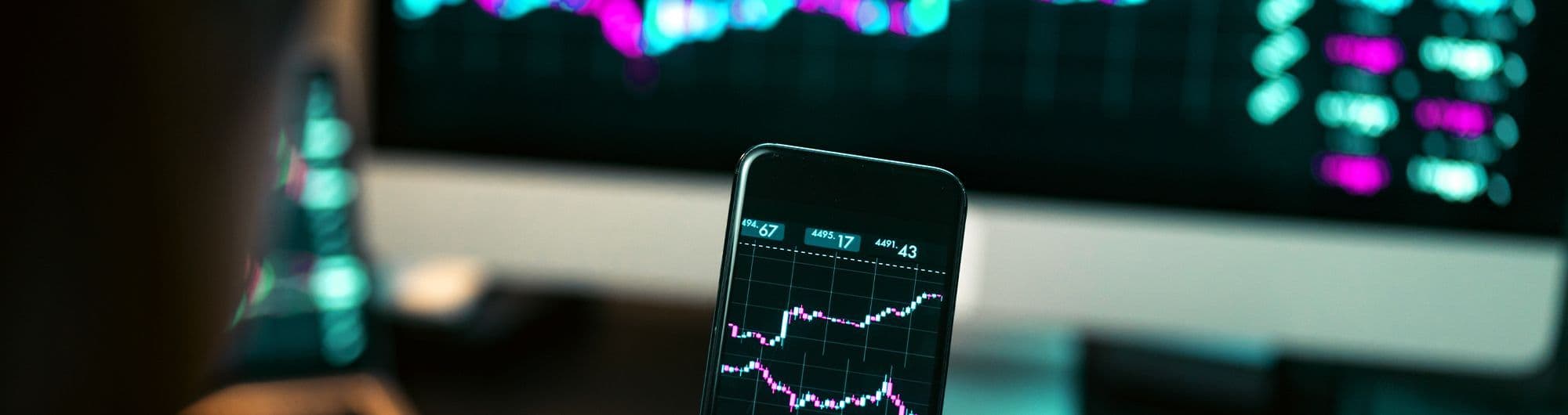 pessoa olhando tela de home broker pelo desktop e celular