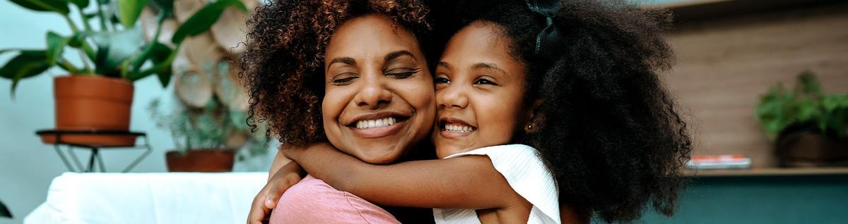 mulher negra adulta e criança negra se abraçando felizes